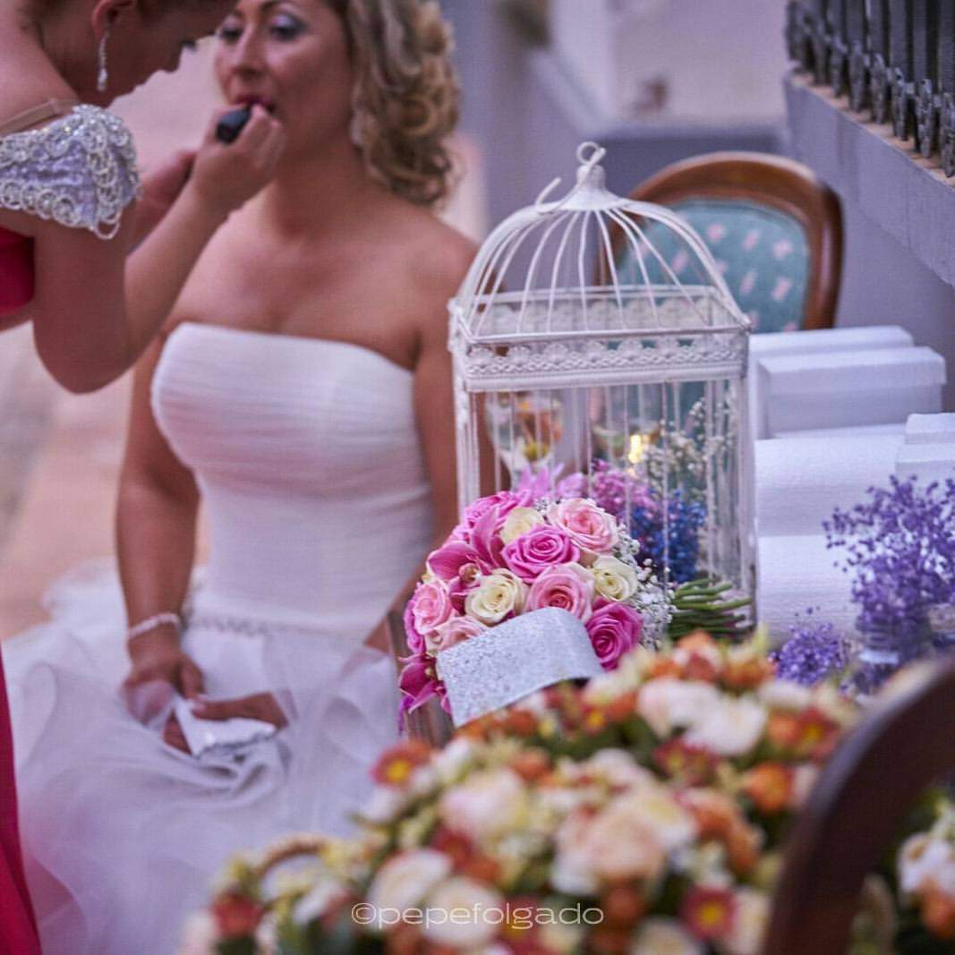 Maquilladora aplicando maquillaje a novia durante boda elegante con detalles florales