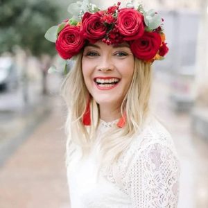 Novia bohemia con corona de flores rojas y vestido de encaje