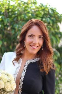 Novia sonriente con peinado suelto y maquillaje natural con ramo de flores