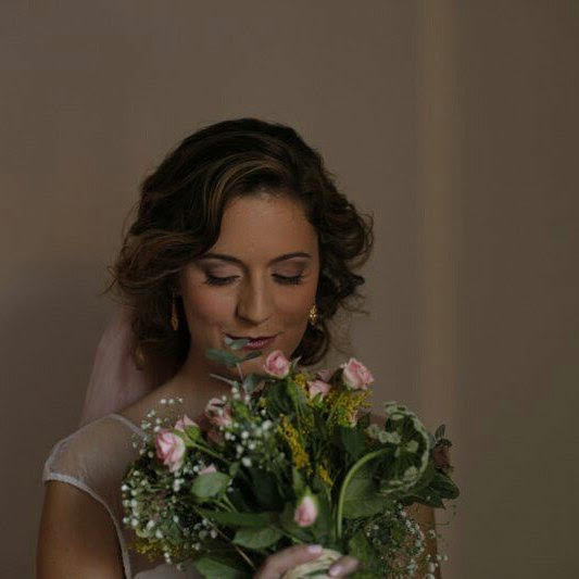 Novia con maquillaje natural mirando su ramo de flores antes de la boda