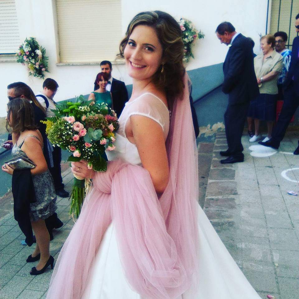 Novia sonriente con maquillaje natural y ramo de flores en su boda