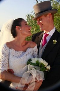 Novios sonrientes al aire libre durante su boda con ramo de flores